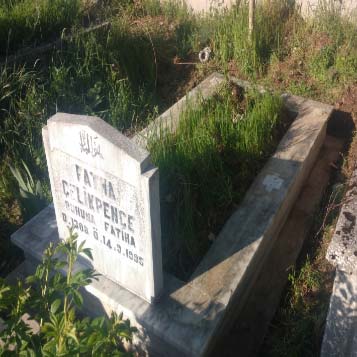 Mezar bakımı peyzaj öncesi resminde, yazıları silinmiş mezar baş taşına sahip bakımsız, eski bir mermer mezar var.